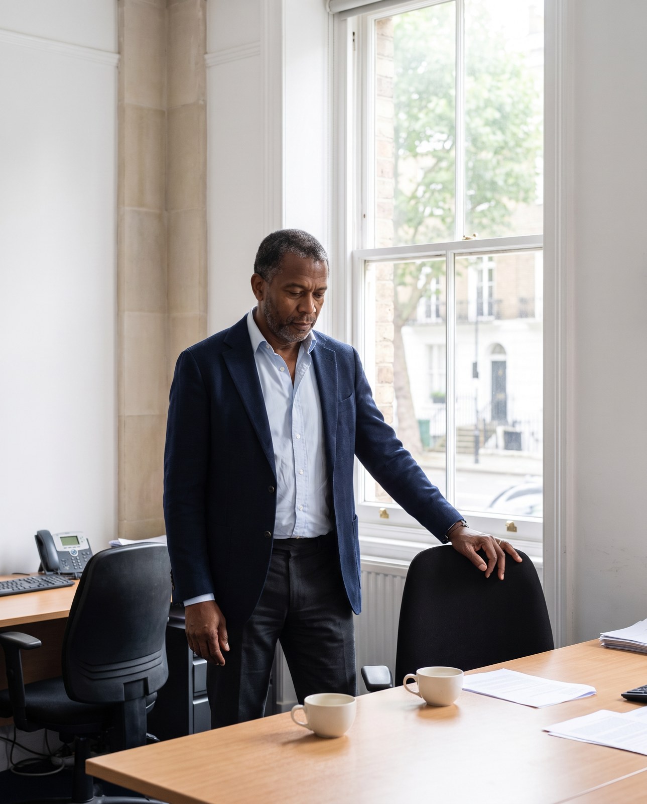 Ashbel standing alone in his office after the compliance officers had left.