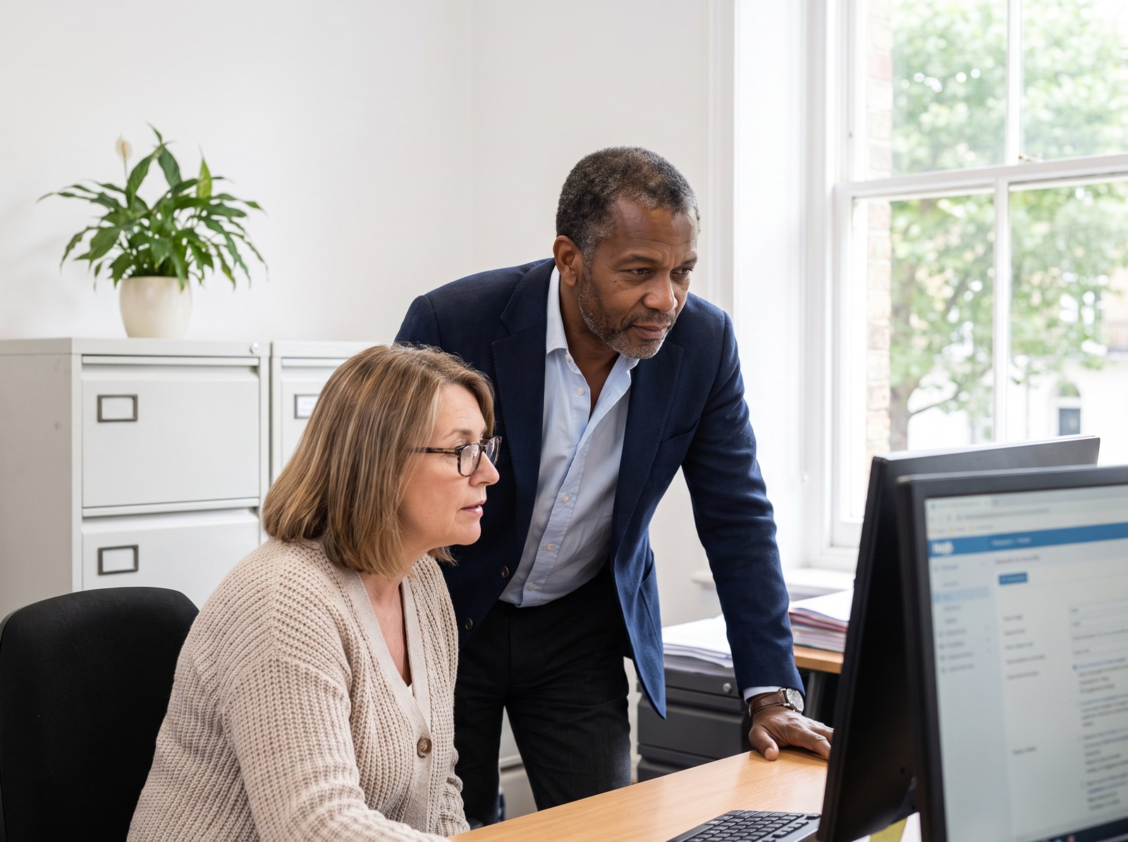 Ashbel and a colleague correcting records at a computer.